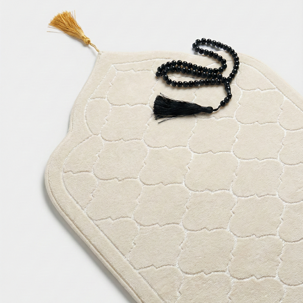 White textured mat with a tassel and black prayer beads on a light gray background